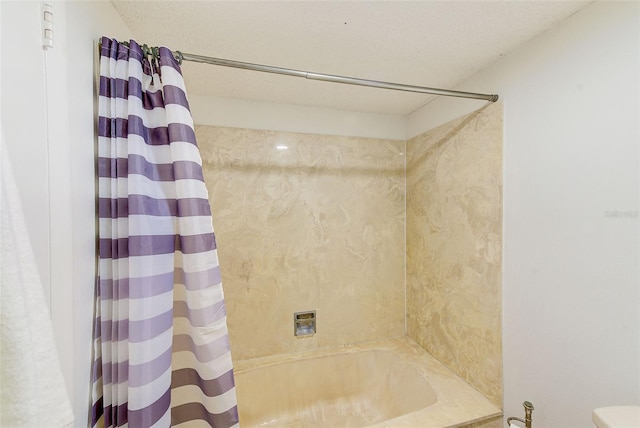 bathroom with a textured ceiling and shower / bath combo with shower curtain