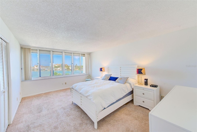 carpeted bedroom with a closet, a water view, and a textured ceiling