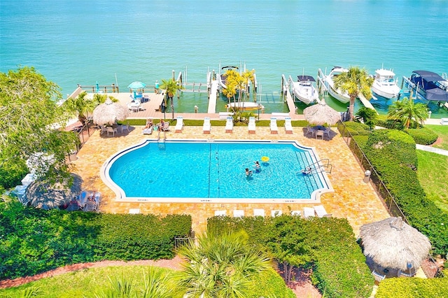 view of swimming pool featuring a dock, a water view, and a patio