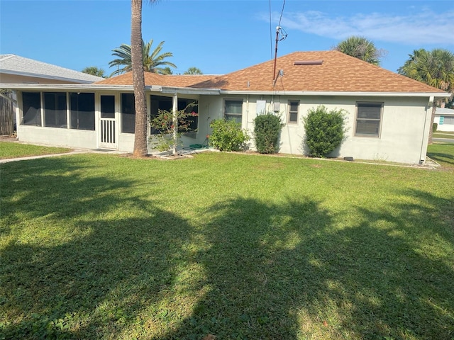 back of property with a sunroom and a yard