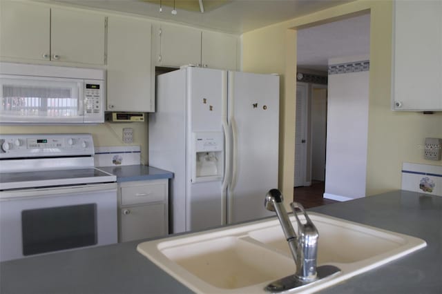 kitchen with white cabinets, sink, hardwood / wood-style floors, and white appliances