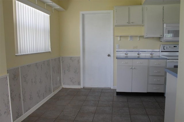 kitchen featuring white appliances, white cabinets, and dark tile flooring