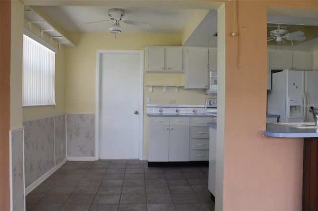 kitchen with white cabinets, ceiling fan, dark tile floors, and white appliances