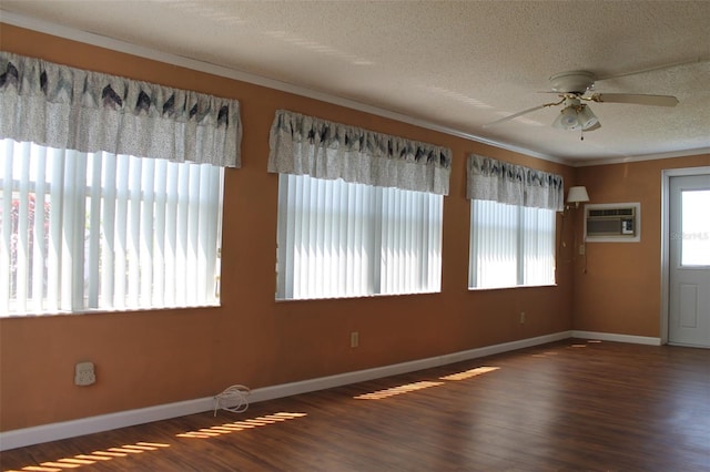 spare room with a textured ceiling, ornamental molding, an AC wall unit, wood-type flooring, and ceiling fan