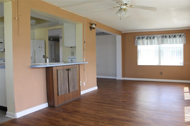 unfurnished living room with a textured ceiling, dark wood-type flooring, and ceiling fan