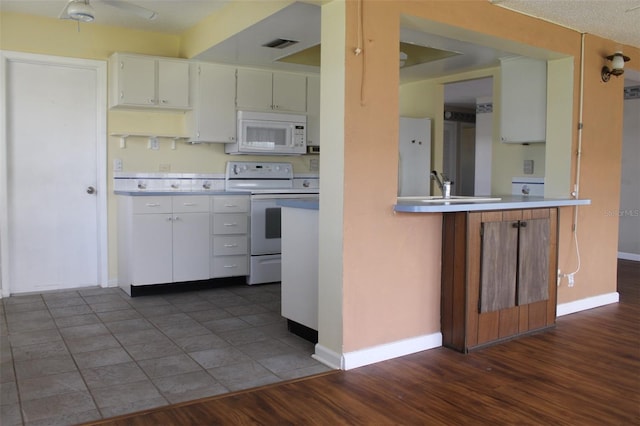 kitchen with white cabinets, white appliances, sink, and dark wood-type flooring