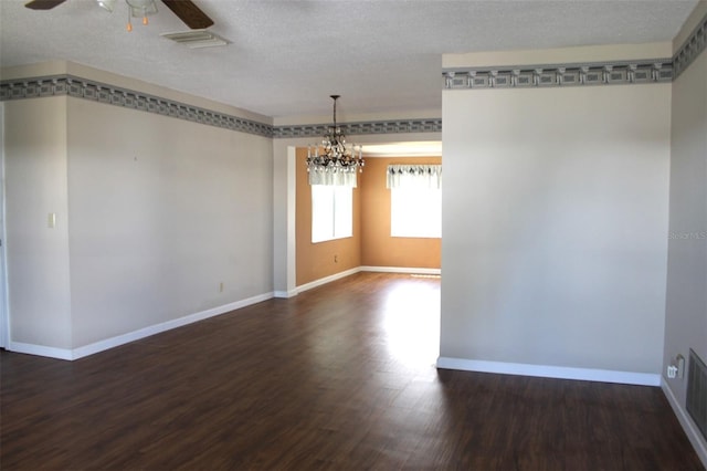 empty room with a textured ceiling, dark wood-type flooring, and ceiling fan with notable chandelier