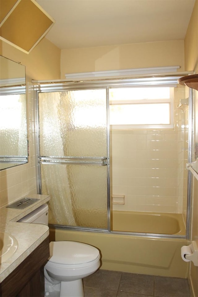 full bathroom featuring tile floors, vanity, toilet, and bath / shower combo with glass door