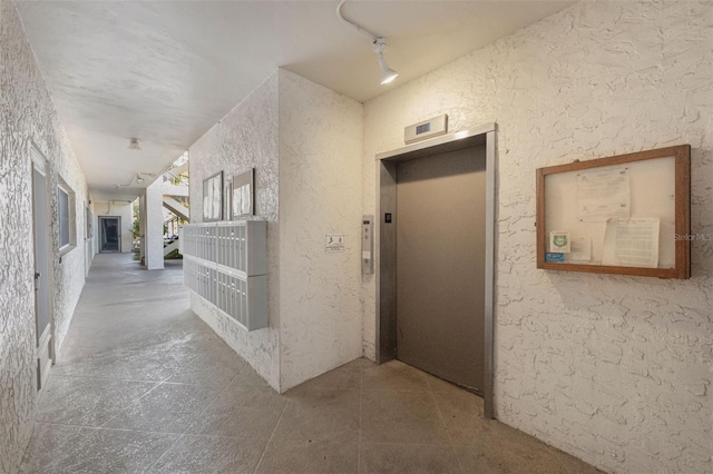 hallway featuring elevator and rail lighting