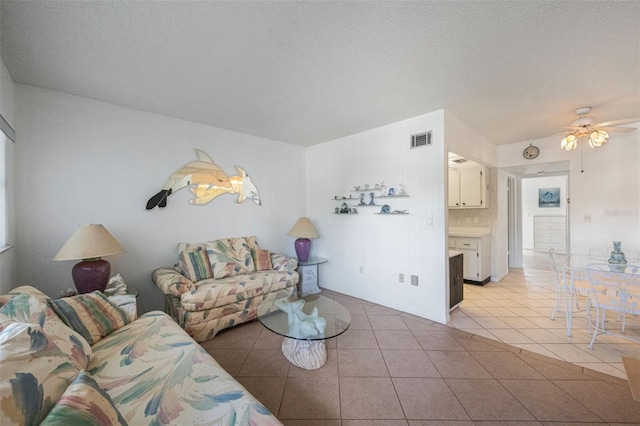 living room featuring a textured ceiling, ceiling fan, and light tile patterned flooring