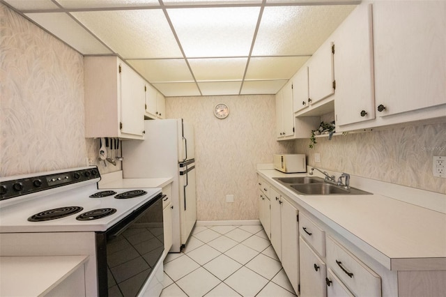 kitchen with a paneled ceiling, white cabinetry, white appliances, and sink