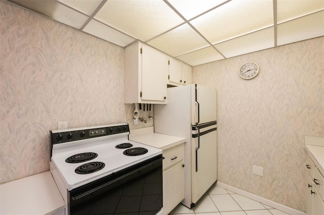 kitchen with light tile patterned floors, white appliances, white cabinetry, and a drop ceiling