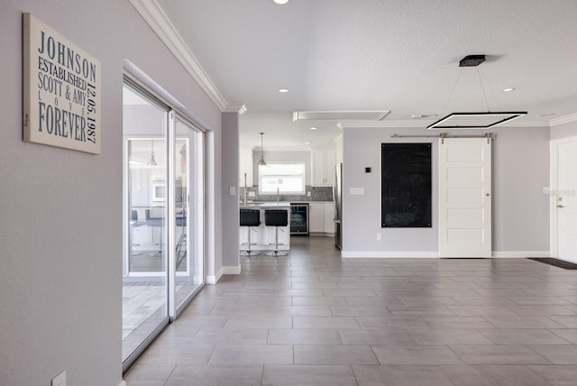 unfurnished living room with beverage cooler, ornamental molding, and baseboards