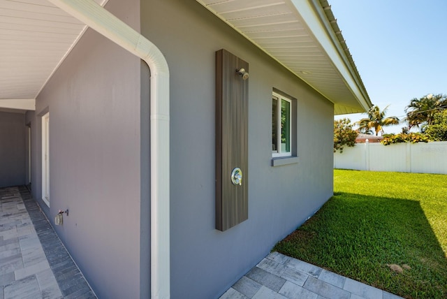 view of side of home featuring stucco siding, a yard, and fence