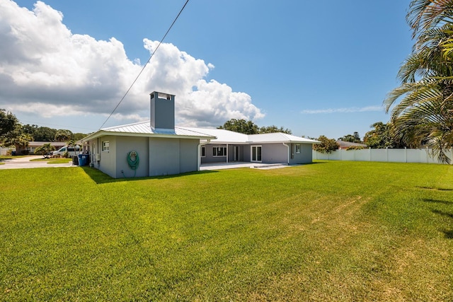 rear view of house featuring metal roof, a lawn, a patio, and fence