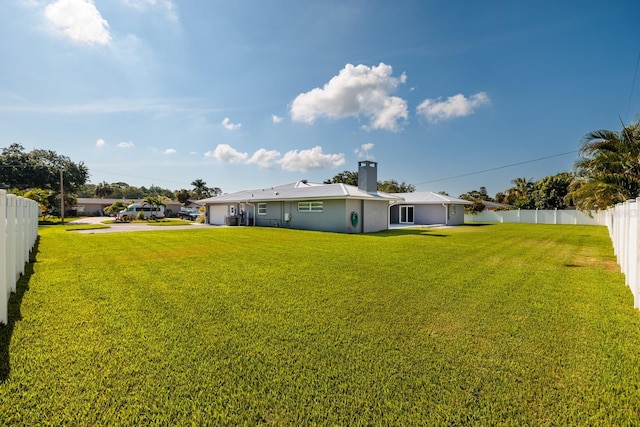 view of yard featuring a garage, a fenced backyard, and concrete driveway