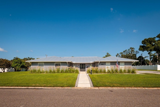 single story home with metal roof, a front yard, and fence