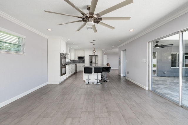 kitchen featuring appliances with stainless steel finishes, white cabinetry, crown molding, and a kitchen bar