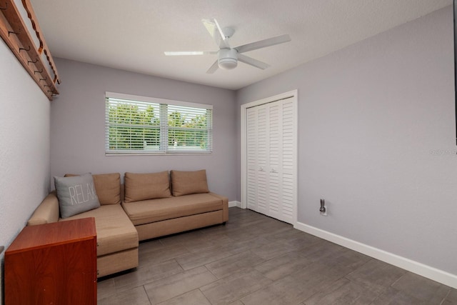 living area featuring ceiling fan, baseboards, and wood finished floors