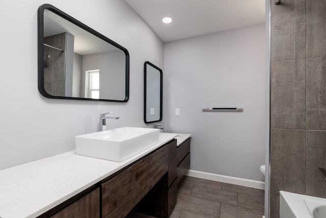 full bathroom with a bathtub, vanity, toilet, and baseboards