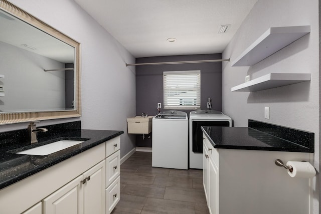 washroom featuring washing machine and dryer, cabinet space, a sink, and visible vents