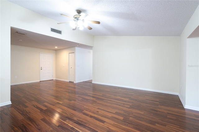 empty room with vaulted ceiling, ceiling fan, dark wood-type flooring, and a textured ceiling