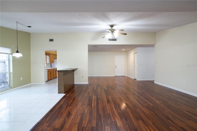 unfurnished living room featuring hardwood / wood-style floors, ceiling fan, and a textured ceiling