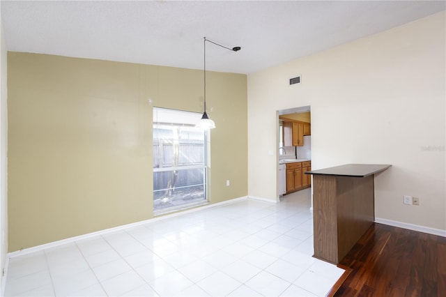 kitchen with kitchen peninsula, light hardwood / wood-style flooring, hanging light fixtures, and sink