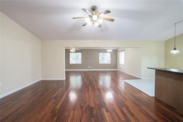 unfurnished room featuring ceiling fan, dark wood-type flooring, and a textured ceiling