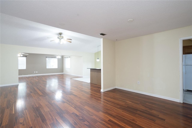 spare room featuring a textured ceiling, ceiling fan, and dark wood-type flooring