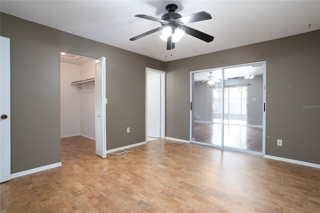 unfurnished bedroom with ceiling fan, light hardwood / wood-style floors, a spacious closet, and a textured ceiling