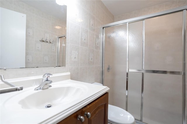 bathroom featuring walk in shower, vanity, and tile walls