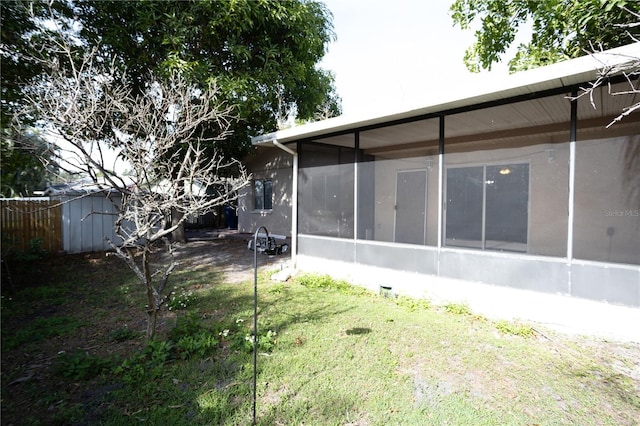 rear view of house featuring a lawn and a sunroom