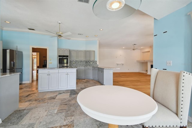 kitchen with ceiling fan, tasteful backsplash, stainless steel appliances, light wood-type flooring, and a center island