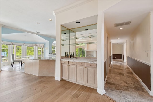 bar featuring light brown cabinets, light stone countertops, light hardwood / wood-style flooring, and pendant lighting