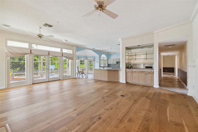 unfurnished living room with ceiling fan, ornamental molding, and light hardwood / wood-style flooring