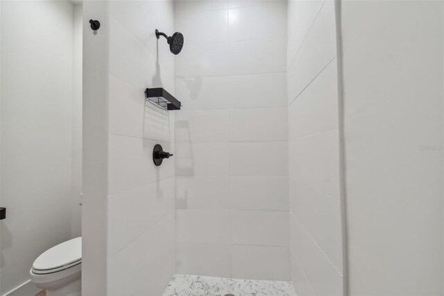 bathroom featuring a tile shower and toilet