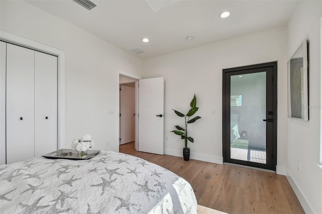 bedroom with access to exterior, light wood-type flooring, and a closet