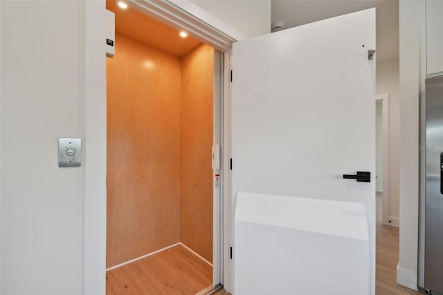 hallway with light wood-type flooring and elevator