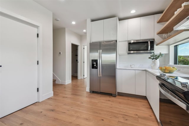 kitchen with white cabinetry, light hardwood / wood-style flooring, and stainless steel appliances