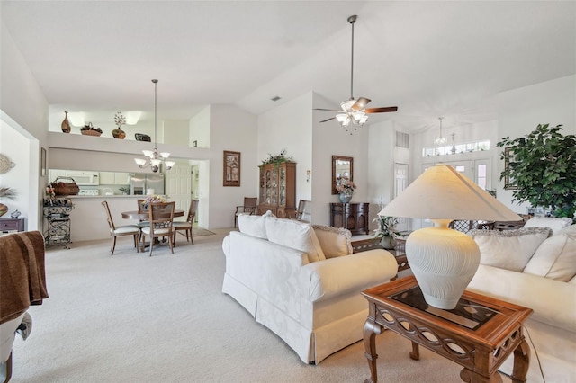 carpeted living room with ceiling fan with notable chandelier and high vaulted ceiling