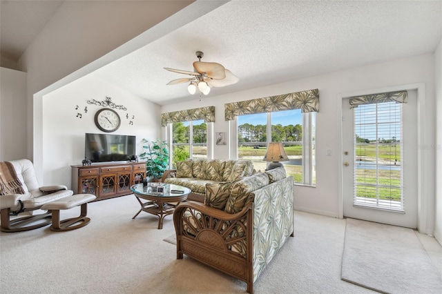 living room featuring ceiling fan, a healthy amount of sunlight, a textured ceiling, and light carpet