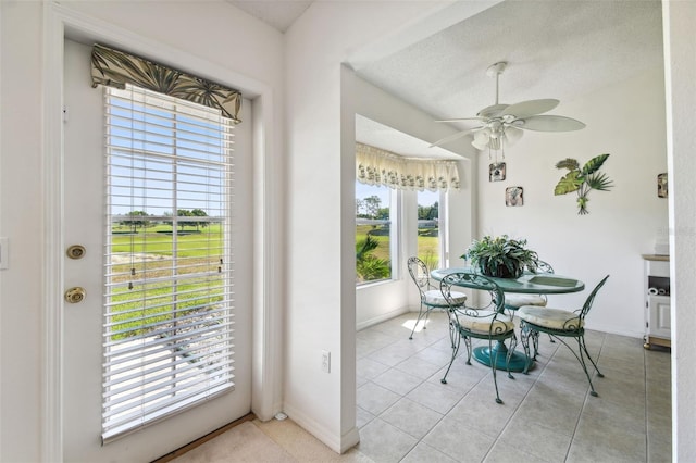 tiled dining room featuring ceiling fan, a healthy amount of sunlight, and a textured ceiling