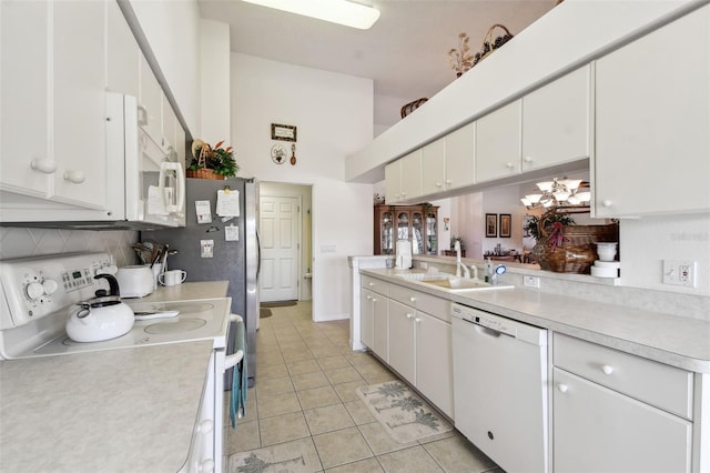 kitchen with sink, light tile patterned floors, backsplash, white appliances, and white cabinets