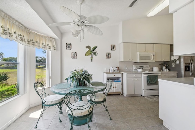 dining space featuring a textured ceiling, ceiling fan, light tile patterned floors, and vaulted ceiling