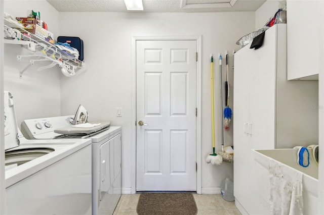 washroom featuring washer and clothes dryer, light tile patterned floors, and a textured ceiling