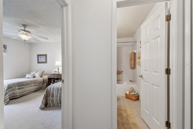 bedroom featuring ceiling fan, light colored carpet, and a textured ceiling