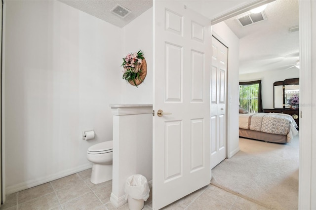 bathroom featuring ceiling fan, tile patterned flooring, a textured ceiling, and toilet