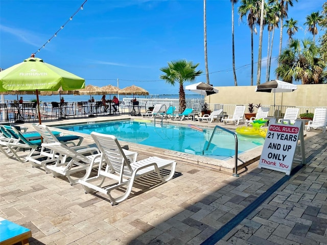 view of swimming pool with a water view and a patio