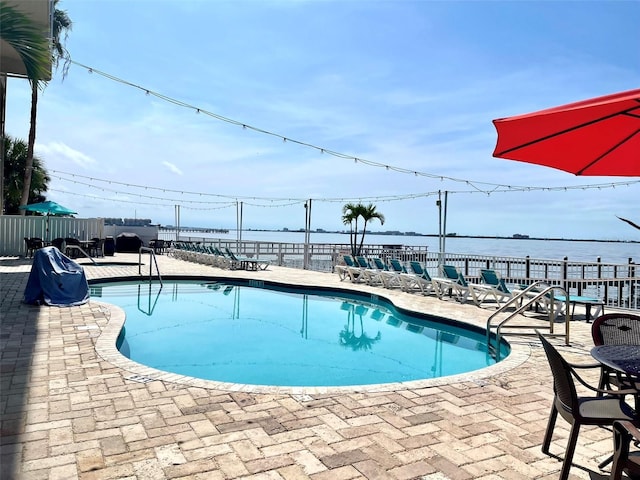 view of pool featuring a patio area and a water view